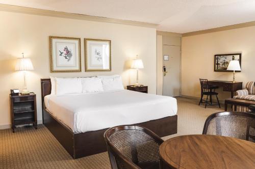 ウィリアムズバーグにあるGriffin Hotel, an official Colonial Williamsburg Hotelのベッド、テーブル、椅子が備わるホテルルームです。
