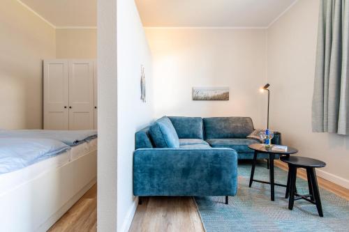 sala de estar con sofá azul y cama en Steger-Hüs Wohnung 15, en Rantum