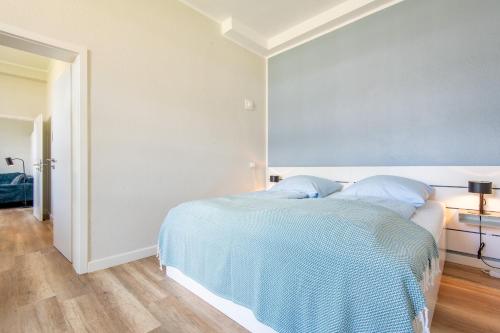 a white bedroom with a bed with blue sheets at Steger-Hüs Wohnung 18 in Rantum