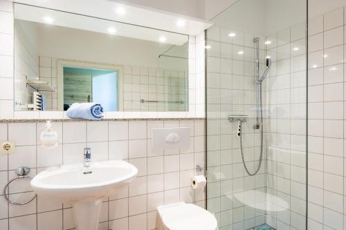 a white bathroom with a sink and a shower at Steger-Hüs Wohnung 18 in Rantum