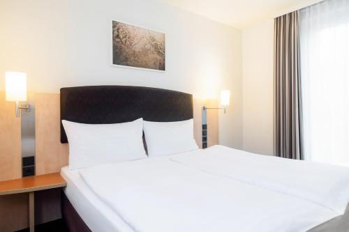 - un grand lit blanc dans une chambre d'hôtel dans l'établissement IntercityHotel Wien, à Vienne