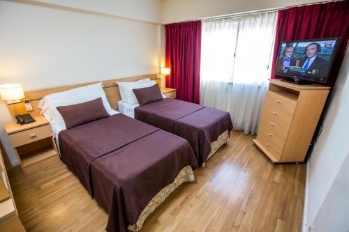 um quarto de hotel com duas camas e uma televisão de ecrã plano em Callao Suites Recoleta em Buenos Aires