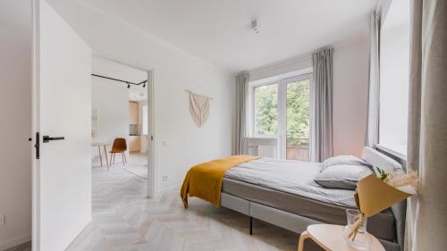 a white bedroom with a bed and a window at Central Apartment in Architectural Street in Kaunas