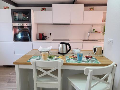 a kitchen with a table and two white chairs at Aros Mountain Lake Iseo Hospitaliy in Pisogne
