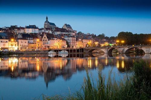 una ciudad con un puente sobre un río por la noche en Le Brumby - Internet Netflix draps serviettes café en Joigny