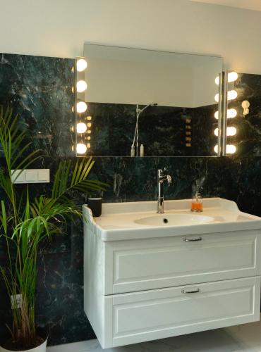 W łazience znajduje się biała umywalka i lustro. w obiekcie Showroom Central Apartment w Szawlach
