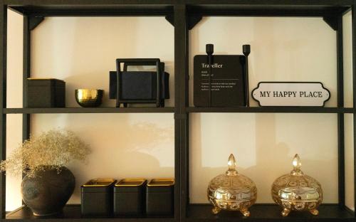 a shelf with two vases and a happy place sign at Showroom Central Apartment in Šiauliai