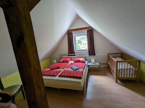 a bedroom with a bed with red sheets and a window at Rekreační dům KRKONOŠE - Ubytování - Holidayhome Lampertice in Lampertice
