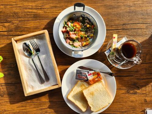 a table with two plates of food and a bowl of soup and toast at AURA Park Resort in Ban Thung Sam Sao