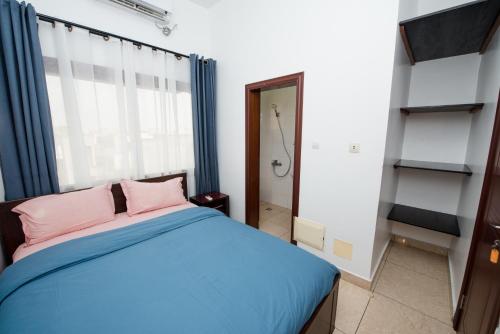 a bedroom with a blue bed with pink pillows at Appartement Charmant et Lumineux in Pointe-Noire