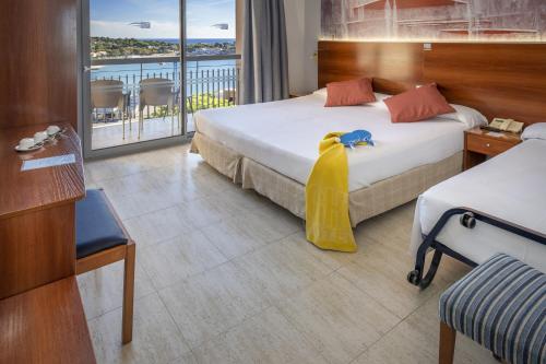 a hotel room with two beds and a balcony at GHT S'Agaró Mar Hotel in Sant Feliu de Guíxols