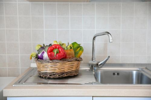マリーナ・ディ・マンカヴェルサにあるAppartamenti Fronte Mareの洗面台の横のカウンターに座る野菜の入ったバスケット