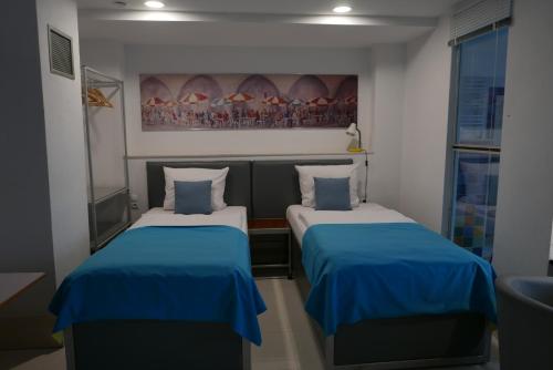 twee bedden in een kleine kamer met blauwe lakens bij ROOMS BYTOM in Bytom