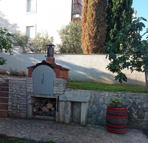 a brick oven sitting next to a wall with a barrel at Apartment MONAS I in Pješčana Uvala 