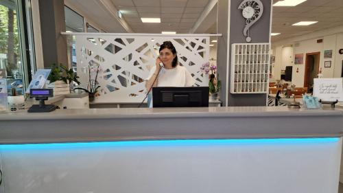 a woman talking on a cell phone behind a counter at Hotel Vienna in Gabicce Mare