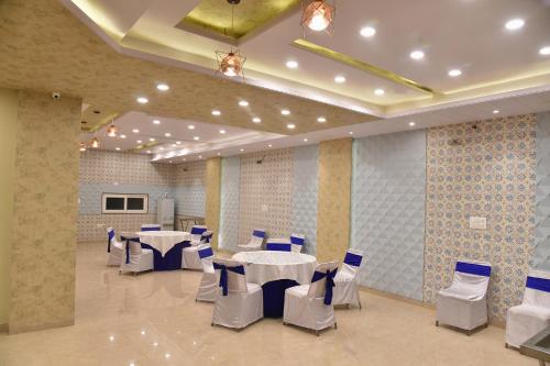 a banquet hall with white tables and blue chairs at FabHotel 7th Crossing Malviya Nagar in Jaipur