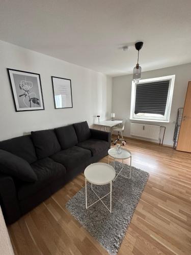 a living room with a black couch and a table at Schöne Wohnung im Herzen von Köln Ehrenfeld in Cologne