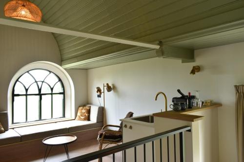 a kitchen and living room with a window and a couch at Kerkhotel Bij De Pastorie in Reitsum