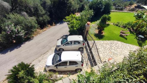 twee auto's geparkeerd op een weg naast een hek bij Villa Amaryllis in Paleokastritsa