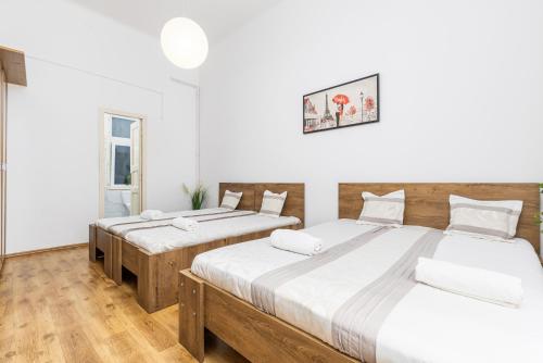 ブダペストにあるReal Apartments Lovagの白い壁とウッドフロアの客室で、ベッド2台が備わります。