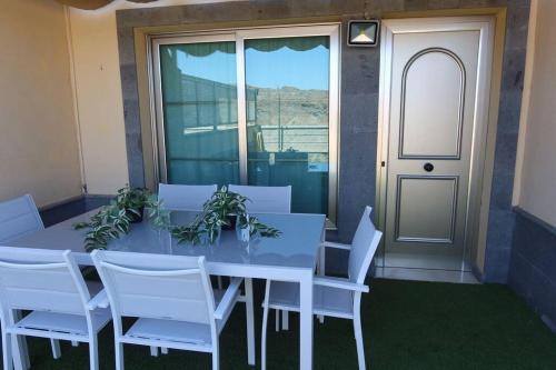 una mesa blanca con sillas blancas y una puerta en Brisas de Puerto Rico, en Puerto Rico de Gran Canaria