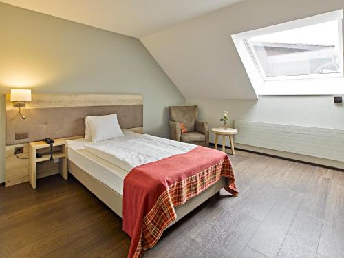 ein Schlafzimmer mit einem Bett, einem Fenster und einem Stuhl in der Unterkunft Restaurant & Hotel Heidelberg in Aadorf