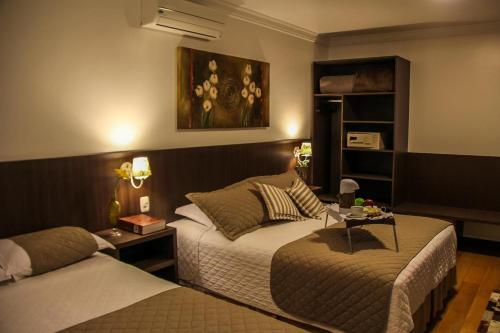 Hotel Premium في غرامادو: غرفة فندقية بسريرين وطاولة