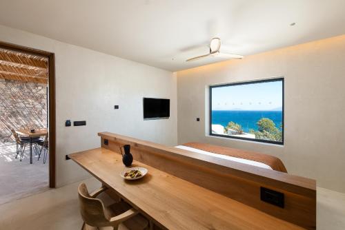 a bedroom with a bed and a large window at KOIA All - Suite Well Being Resort - Adults Only in Agios Fokas