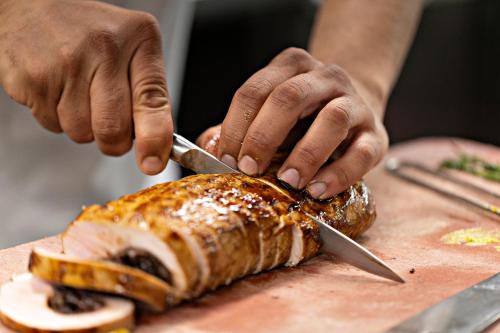 a person cutting a fish with a knife on a cutting board at Restaurant & Hotel Heidelberg in Aadorf