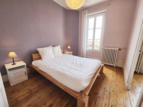 une chambre avec un grand lit et une fenêtre dans l'établissement Le Bienheureux, le calme en ville et jardin, à Angoulême