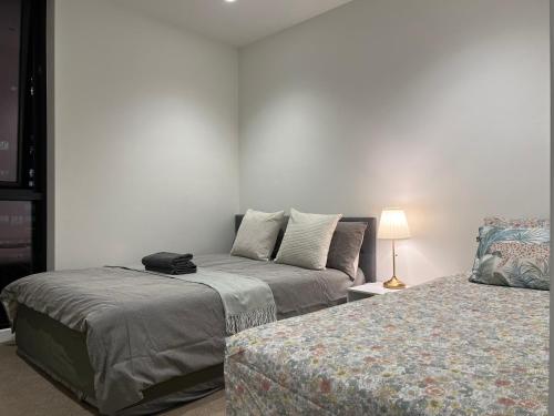 a bedroom with two beds and a lamp on a table at Quiet CBD 3b2b apartment + free parking in Melbourne