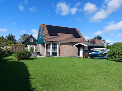 una casa con techo solar y un barco en el patio en 't Zyper Eilant 123, en Oudesluis