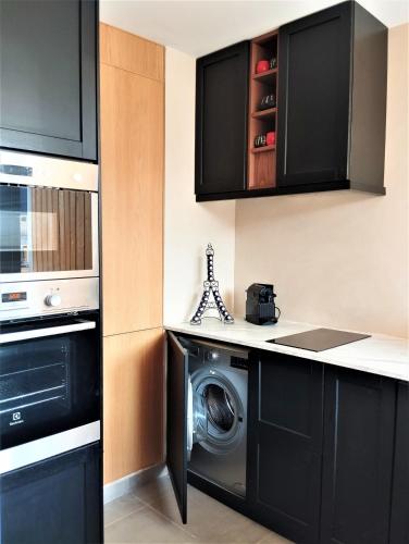 - une cuisine avec des armoires noires et un lave-linge dans l'établissement Elegant 48sqm apartment Eiffel - view & large terrace, à Paris