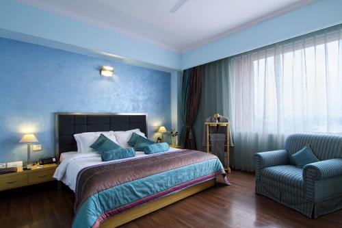 um quarto com uma cama grande e uma cadeira em The Piccadily em Lucknow