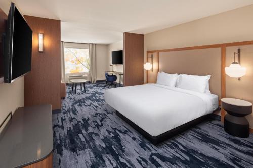 YanktonにあるFairfield by Marriott Inn & Suites Yanktonの白いベッドとデスクが備わるホテルルームです。