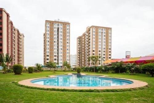 a swimming pool in a park with tall buildings at Bella Vista at Enzi Heights along Mombasa Rd next to Nextgen close to JKIA in Nairobi