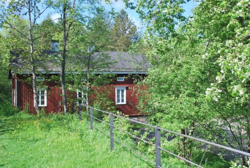 a red house in the woods with a fence at Kirjakkalan Ruukkikylä in Teijo