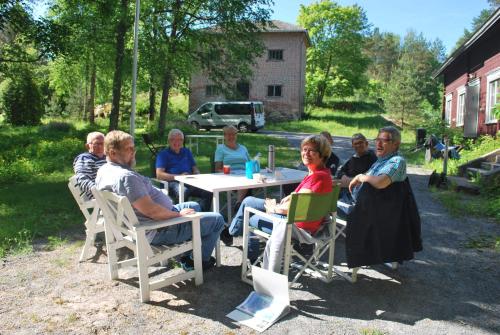 a group of people sitting at a table in a yard at Kirjakkalan Ruukkikylä in Teijo