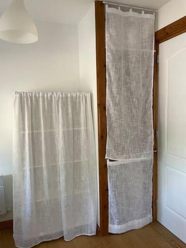 a window with a curtain next to a door at Le Gîte de L'Orée du Morvan in Montberthault