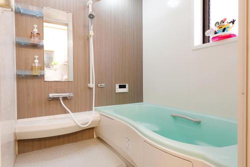 a bathroom with a bath tub and a sink at Bello House Imabari in Imabari
