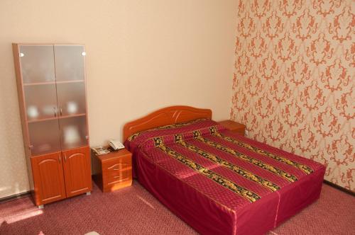a bed room with a red bedspread and a red dresser at Hotel Kolibri in Abakan