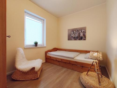 a bedroom with a bed and a window and a chair at Haus am Meer 63 in Kaltenhof