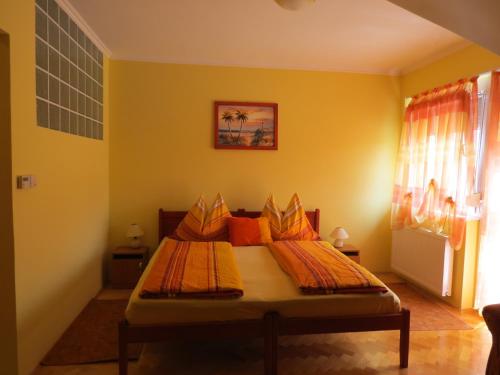 a bedroom with a bed with yellow walls at Jázmin Apartman in Harkány