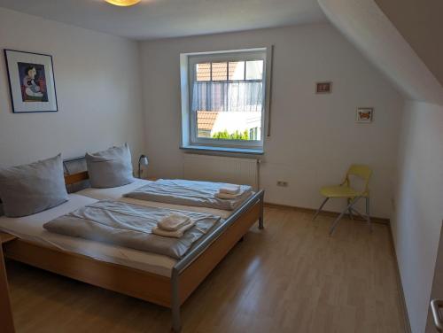 een slaapkamer met een bed met een raam en een stoel bij Haus Christof - Hooksiel in Wangerland
