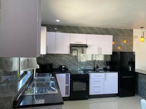a kitchen with white cabinets and black appliances at Swiss Luxury Apartments in Ndola