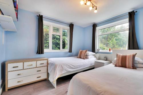 - 2 lits dans une chambre aux murs bleus et aux fenêtres dans l'établissement Pass the Keys Large family home in picturesque village, à Westerham