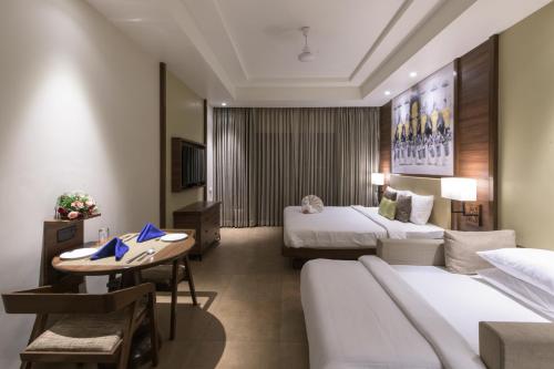 Club Mahindra Ashtamudi في Nīndakara: غرفة فندقية بسريرين وطاولة