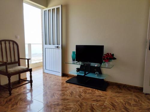 un salon avec une télévision, une chaise et une table dans l'établissement Casa Andrade Delgado - Rotxa Grande, à Ponta do Sol