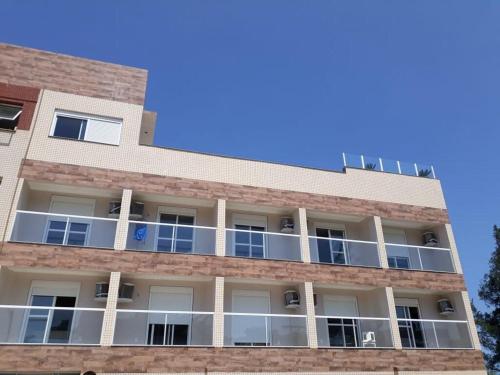 an apartment building with balconies and a blue sky at Hotel Jardim do Mar in Torres