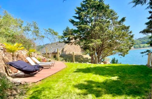 une pelouse avec deux chaises longues et l'eau dans l'établissement Évasion Prestige sur l'Île Koeur, à Lézardrieux